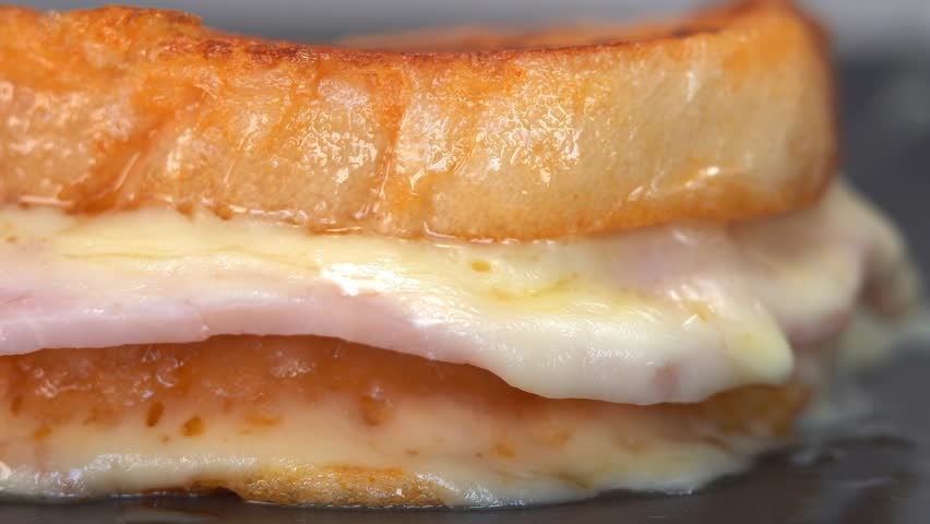 Close up of knife cuts sandwich with cheese and ham. French toast with melted cheese for breakfast. Food background