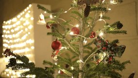 Close up of a Christmas tree with baubles, pinecones, and glowing string lights - Powered by Shutterstock - Get 15% off with code: PIKWIZARD15