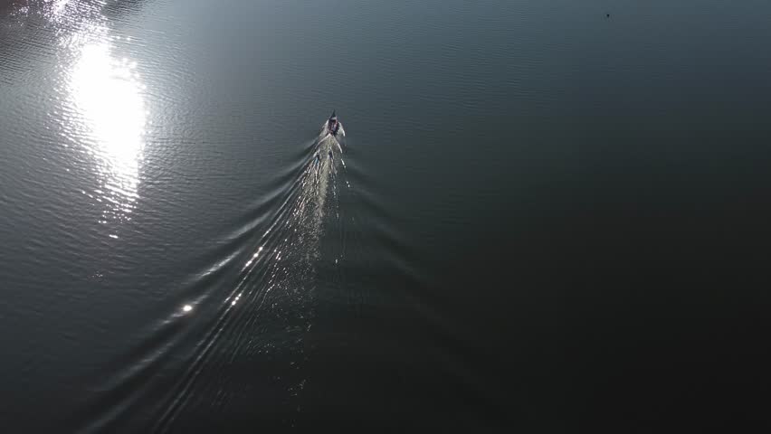 aerial view of boat and two canoers gliding on reflective water