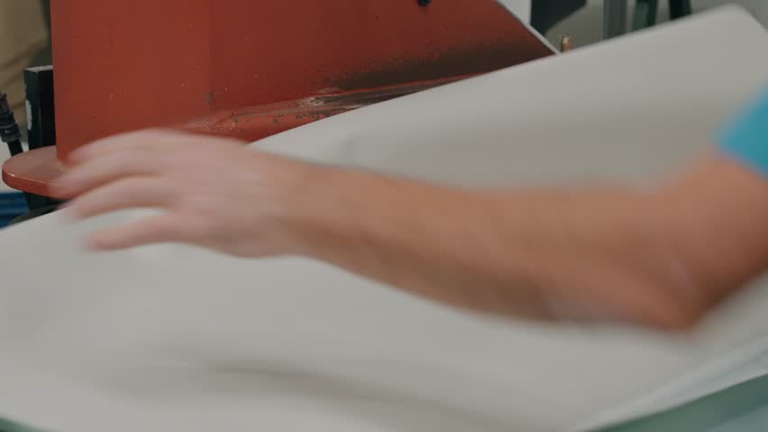 worker cutting textile sheets using industrial press equipment