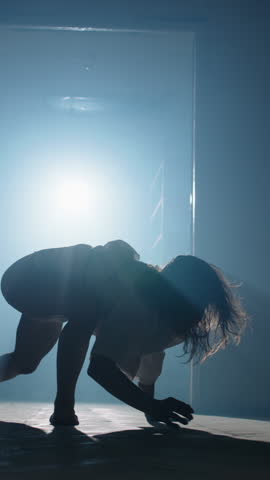 Creepy woman in hospital gown enters corridor with jerky movements bends into backbend and approaches camera swaying in disturbing horror scene with zombie and halloween fear