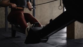 Female athlete in burgundy leggings and athletic shoes using indoor rowing machine in dimly lit functional fitness gym  - Powered by Shutterstock - Get 15% off with code: PIKWIZARD15