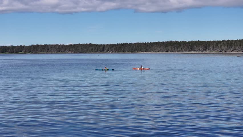 Two People in Kayaks Paddle Against the Current on a Summer Day in Anticosti, Quebec, Canada