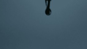 Single water droplet falls in slow motion with soft stormy background - Powered by Shutterstock - Get 15% off with code: PIKWIZARD15