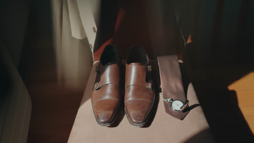 Close up of brown shoes tie and pocket watch in wedding preparation scene