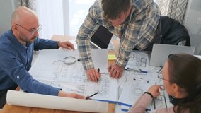 Architects and engineers gathered at office desk analyzing blueprints. Group points to technical drawings, sharing ideas and discussing project details in teamwork environment. - Powered by Shutterstock - Get 15% off with code: PIKWIZARD15