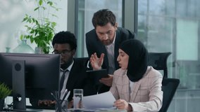 Diverse business team arguing in office angry discussion documents computer work conflict Muslim woman in hijab African Caucasian male colleagues stressed teamwork problem multiracial three co-workers - Powered by Shutterstock - Get 15% off with code: PIKWIZARD15