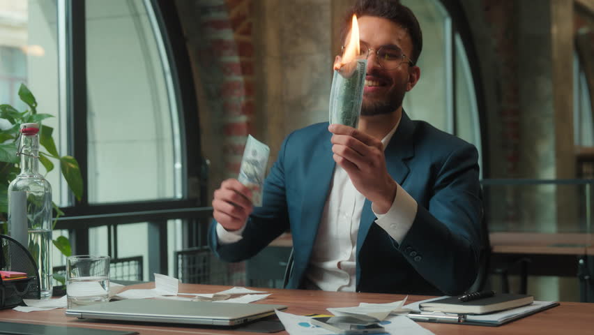 Happy Hindu business man burning money in office laughing male Arabian Indian businessman crazy mad executive entrepreneur CEO investor fooling having fun burn cash dollars salary spending finance