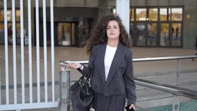 A determined and ambitious businesswoman with beautiful curly hair stands confidently in a stylish gray suit, embodying professionalism and elegance, inspiring others to strive for greatness - Powered by Shutterstock - Get 15% off with code: PIKWIZARD15