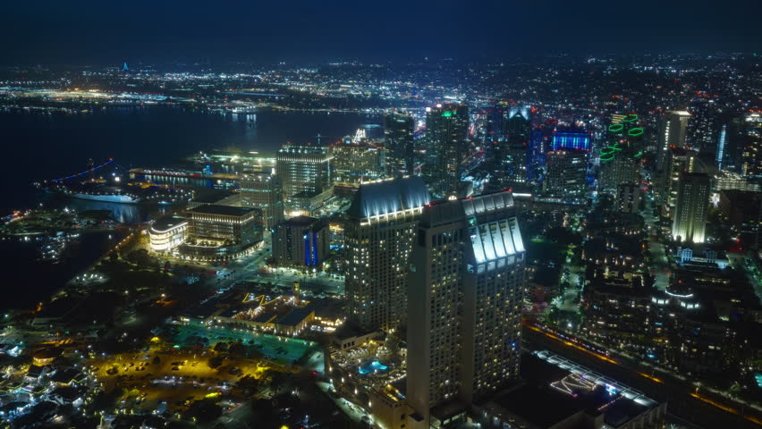 Experience the stunning night aerial view of Downtown San Diego at dusk, where twinkling lights illuminate the skyline and coastline, showcasing the citys urban beauty and vibrant atmosphere