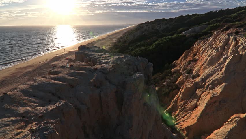 Sunset over Arenosillo cliffs and sandy beach in Doñana, Huelva, Spain. Scenic coastal view, ocean horizon, travel, and nature background.