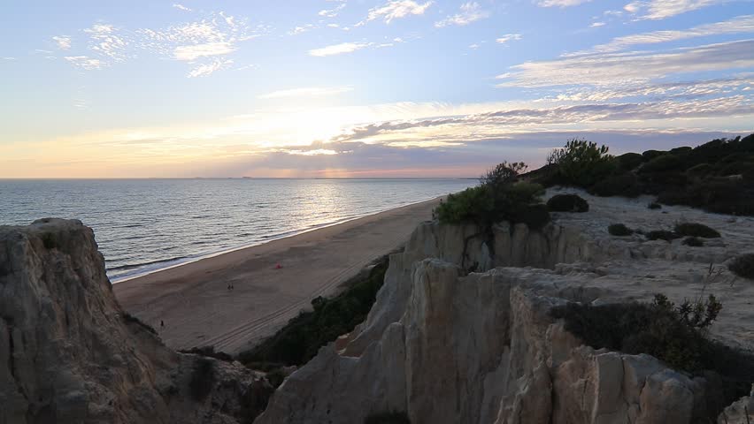 Sunset over Arenosillo cliffs and sandy beach in Doñana, Huelva, Spain. Scenic coastal view, ocean horizon, travel, and nature background.