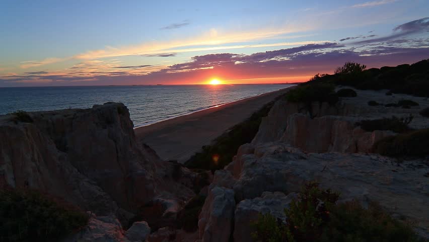 Sunset over Arenosillo cliffs and sandy beach in Doñana, Huelva, Spain. Scenic coastal view, ocean horizon, travel, and nature background.