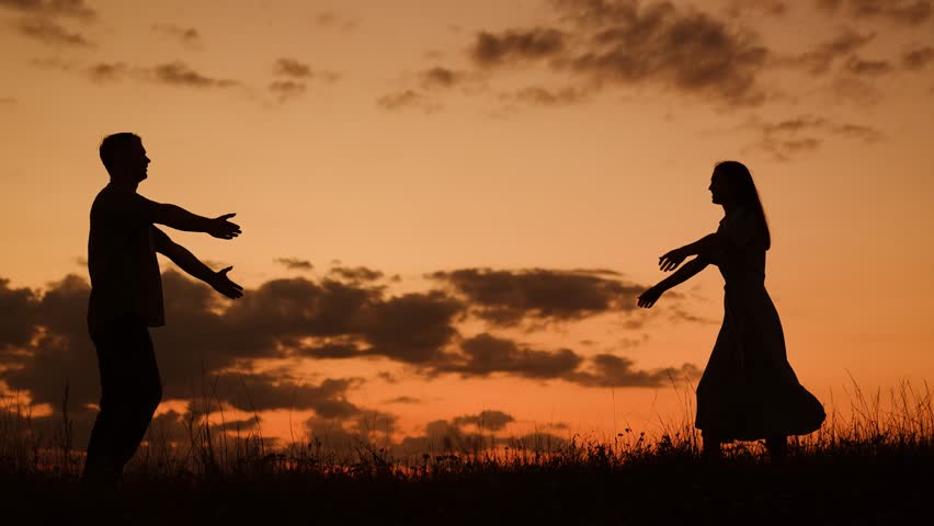 Couple in love meets in nature. Silhouettes of man woman walking toward each other, loving couple embracing at sunset, slow motion. Love story happy family. Romantic date love of happy couple in park