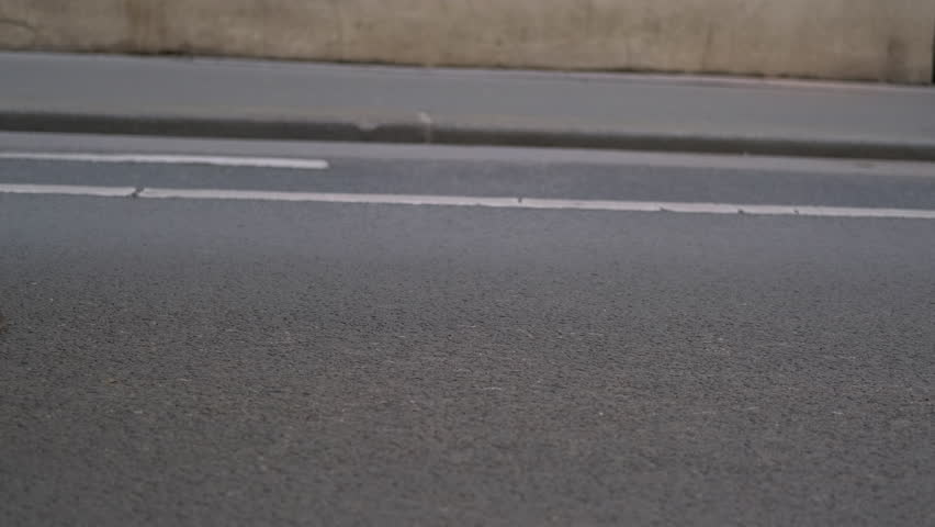 Horse pulling carriage walking on asphalt road. Closeup of hooves and wheels in motion showcases a horse pulling a carriage along a paved road.