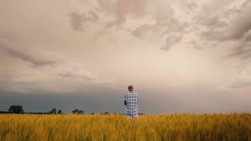 A Young Farmer Stands Alone In A Field Of Wheat Against A Stormy Sky 4k video