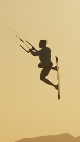 Kite surfer jumping over ocean waves in slow motion golden hour tropical sunset extreme sport freedom lifestyle travel destination adventure holiday energy summer beach paradise motivation