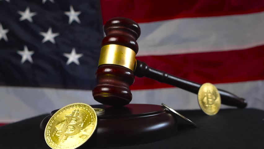 Law and justice court brown and bronze colored wooden hammer with golden shiny and reflective Bitcoin cryptocurrency money coins in front of a American United States of America flag. Federal reserve.
