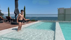 Boy jumps into outdoor pool on a sunny summer day, captured mid-air moment. Clear blue water, seaside hotel, fun vacation activity - Powered by Shutterstock - Get 15% off with code: PIKWIZARD15