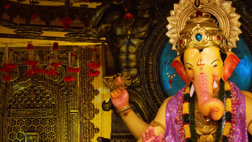 Beautiful Lord Ganesha idol adorned with ornaments and flowers inside a decorated temple.