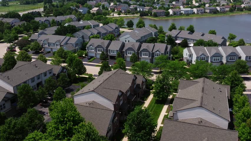American suburban multifamily homes with green yards and clean roads along lake, idyllic neighborhood no people nobody around, aerial establish