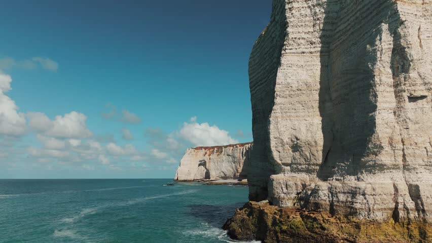 Drone fly-past of foreground cliffs revealing the natural arch of Étretat in Normandy, France.