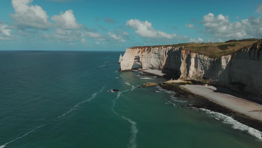Drone shot of Étretat’s white chalk cliffs and natural arch stretching along the Normandy coast.