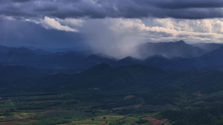 Dramatic Mountain Landscape with Rainfall and Sunlit Clouds in the Distance