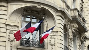 A video shows the flag of France fluttering gently in the wind atop a majestic, classical building. The blue, white, and red vertical stripes are clearly visible as the flag billows against a dramatic - Powered by Shutterstock - Get 15% off with code: PIKWIZARD15