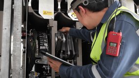 Asian male engineer using digital tablet to inspect industrial machinery in power plant, wearing helmet and safety vest, focusing on maintenance, quality control, and workplace safety in engineering - Powered by Shutterstock - Get 15% off with code: PIKWIZARD15