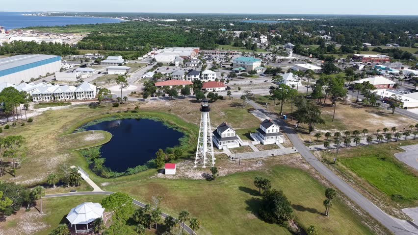 Drone orbit around Cape San Blas Lighthouse and local houses near shoreline and artificial pond, Port St. Joe, Gulf County, Florida, USA