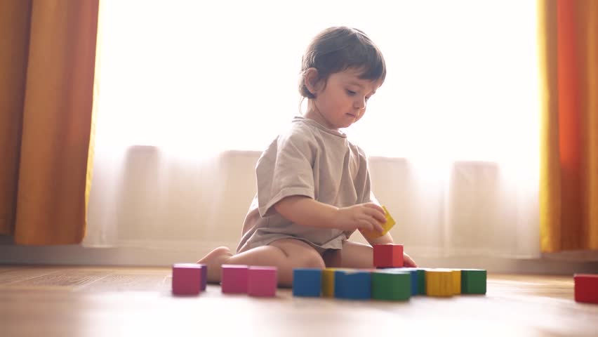 small child playing home. happy and full of joy childhood, children's dream concept. beautiful little lifestyle girl sitting on the floor and playing with colorful cubes