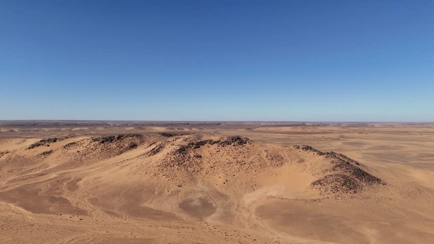 Drone aerial view of the Eye of the Sahara in Mauritania, an iconic natural wonder with striking circular patterns in the vast desert landscape against blue sky