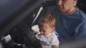 dad plays with his son in car. people family and children concept. beautiful little kid sit and plays on his father's lap and turn the steering lifestyle wheel of his car - Powered by Shutterstock - Get 15% off with code: PIKWIZARD15