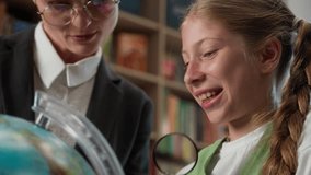 Happy laughing curious Caucasian teenager junior school little girl child smiling student kid schoolgirl study geography globe world map magnifying glass with teacher female woman professor classroom - Powered by Shutterstock - Get 15% off with code: PIKWIZARD15