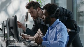 Diverse callcenter collaboration Caucasian boss explaining task pointing finger African operator headset Indian female work computer business call center customer support office communication training - Powered by Shutterstock - Get 15% off with code: PIKWIZARD15