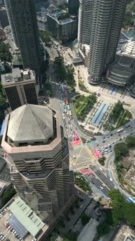Aerial view of busy city intersection in central Kuala Lumpur, Malaysia. Surrounded by modern skyscrapers with traffic and urban architecture. Themes of city life, travel, and modern Asia.