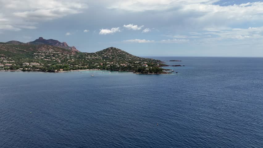 flying across Agay Bay, French Riviera (Côte d'Azur) with left paning from "Phare d'Agay" along coastline to Beach  "Agay Plage" and  "Massif de l'Esterel" in background - 4k aerial video footage