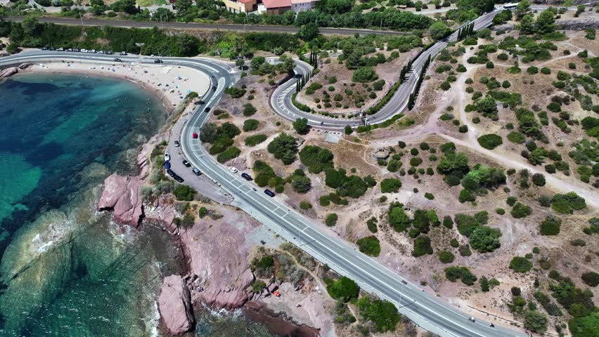 aerial view,  flying along Agay Bay coastline, French Riviera (Côte d'Azur) with "Plage du Pourrousset"  near Village Cap Estérel in Saint-Raphaël, with cars driving on the costal road - 4k footage 