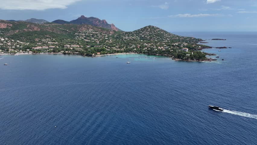 panning left across Agay Bay, French Riviera (Côte d'Azur) from  "Phare d'Agay" along coastline to Cap Esterel and Cap Dramont with  "Massif de l'Esterel" in background - 4k aerial video footage