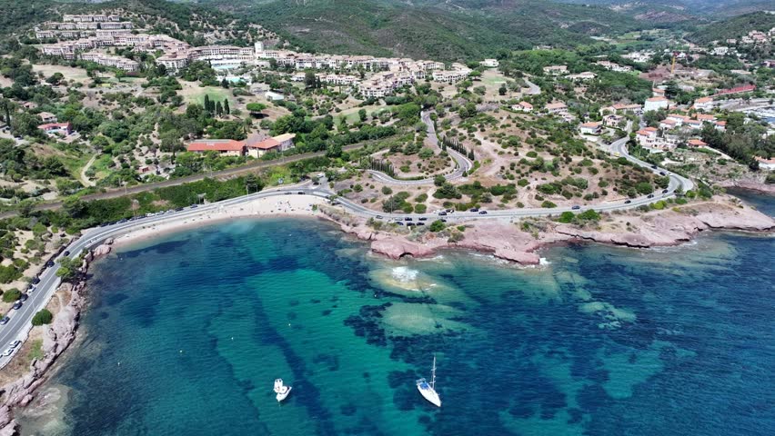 aerial view,  flying along Agay Bay coastline, French Riviera (Côte d'Azur) with "Plage du Pourrousset" , Village Cap Estérel in Saint-Raphaël, and panning left to Cap Dramont  - 4k video footage 
