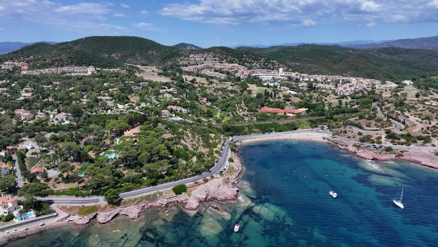 aerial view,  flying along Agay Bay coastline, French Riviera (Côte d'Azur) towards "Plage du Pourrousset"  with left panning from Village Cap Estérel in Saint-Raphaël to Cap Dramont - 4k footage 