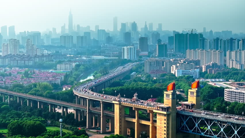Aerial shot of a large bridge with busy traffic flowing into the modern urban cityscape and financial district of a major city in Nanjing.