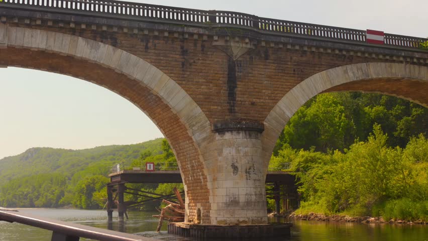 Shot of passing under stone bridge over Dordogne river, France. View from a traditional boat (gabare in French)