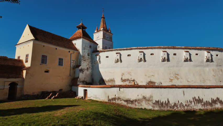 Harman Fortified Church, Harman, Transylvania, Romania, combines a white walled church, defensive ring, and robust tower, enclosing a calm courtyard that reflects centuries of community life

