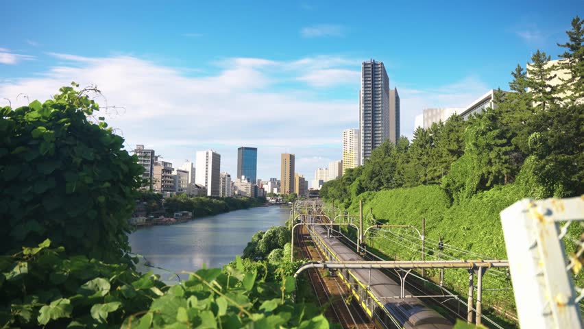 Tokyo Japan, Long JR Train Traveling Past River With City Background