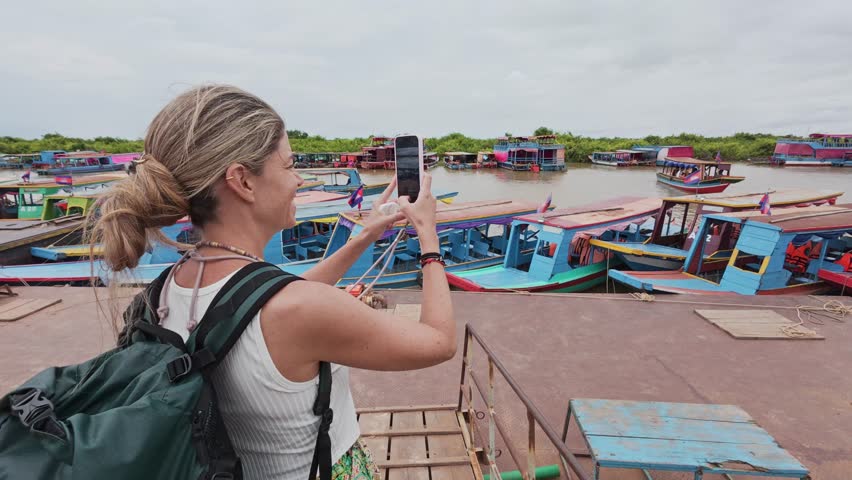 Female tourist photographing colorful boats in cambodia