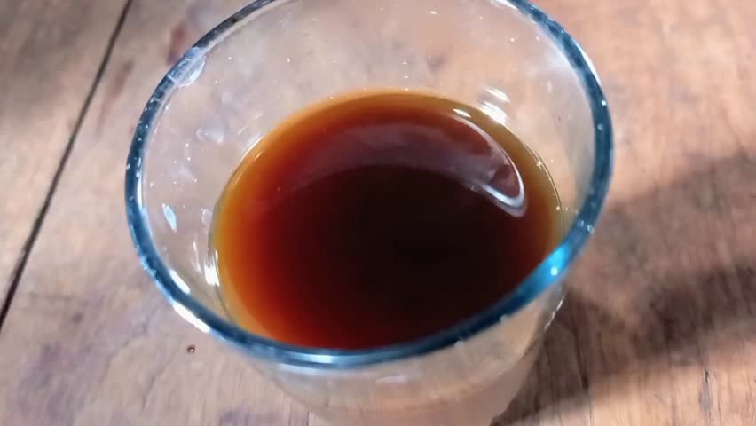 Banyuwangi 19 September 2025 - a glass of hot Americano coffee on an old teak table