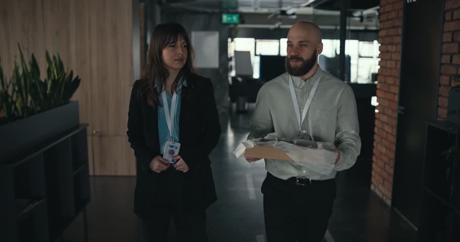 Three office colleagues with badges bring pastries and share them with seated coworkers in a modern workspace during a friendly casual break or lunch time