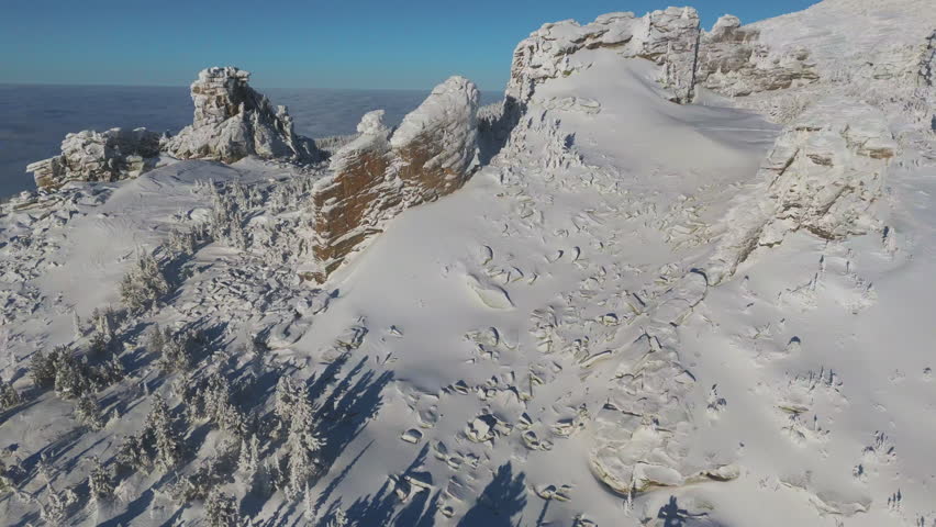 Aerial view circles red sandstone towers on the Sheregesh crest. Wind carved cornice, long shadow and sparkling frost unfold in steady motion, perfect for travel, tourism and resort promo